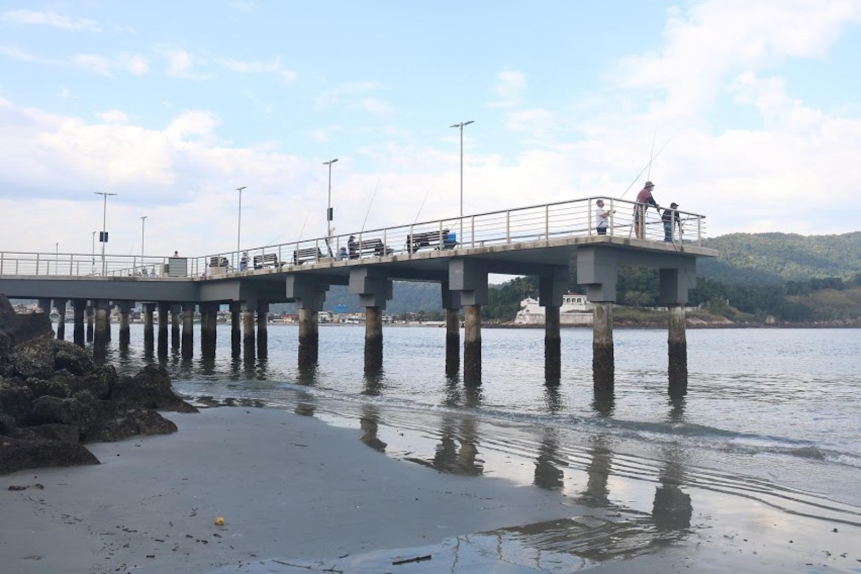 O deck do pescador visto de longe com a maré baixa. #paratodosverem