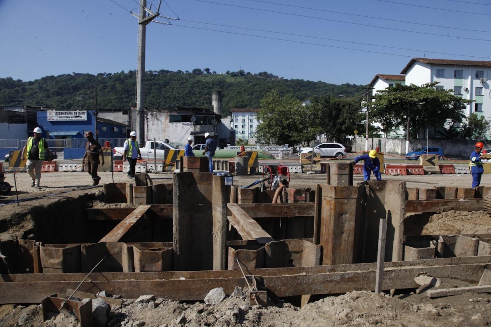 Obras em andamento. Homens estão próximos a grande escavação. #Paratodosverem