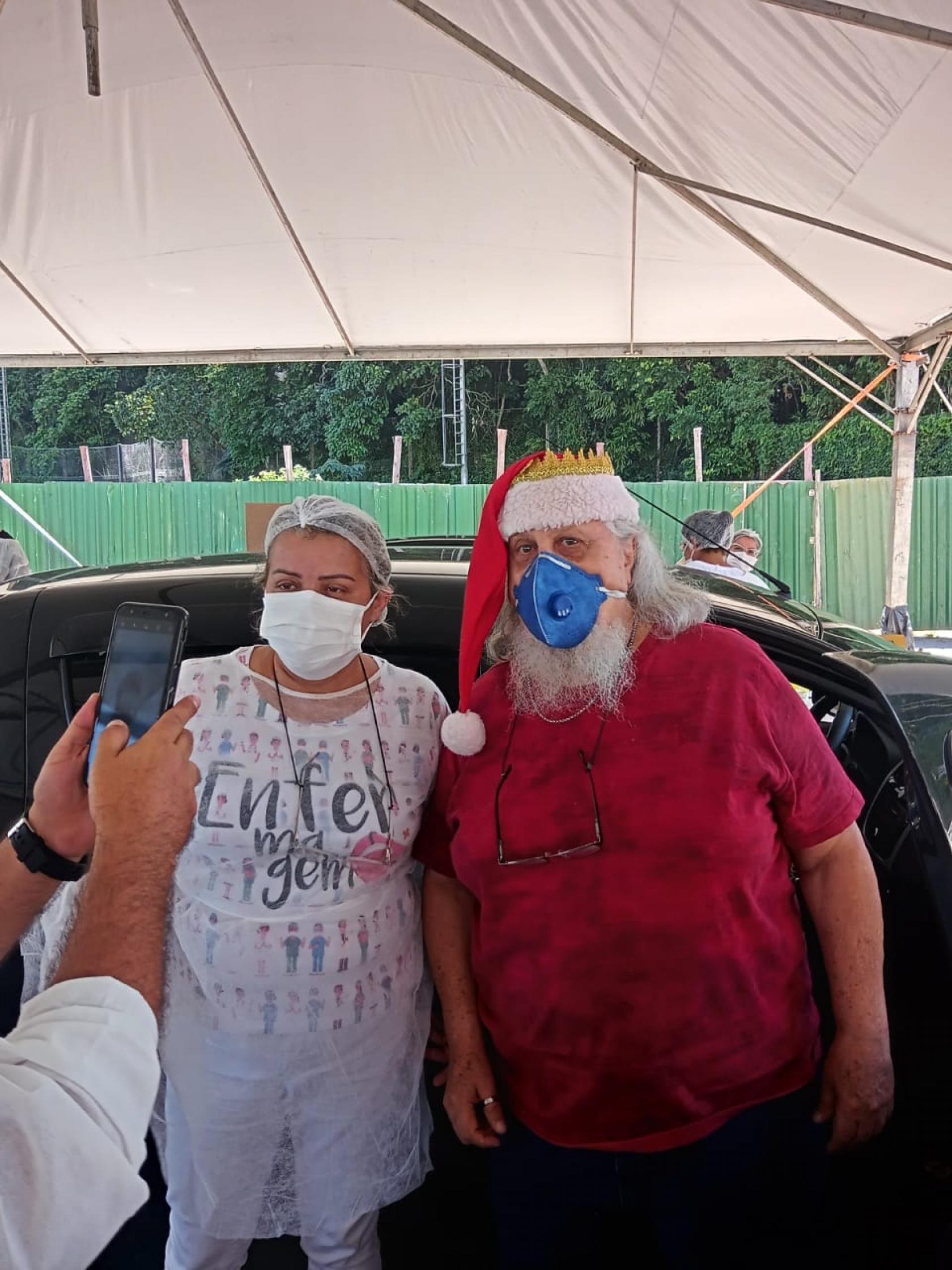 papai noel posa ao lado de enfermeira #paratodosverem