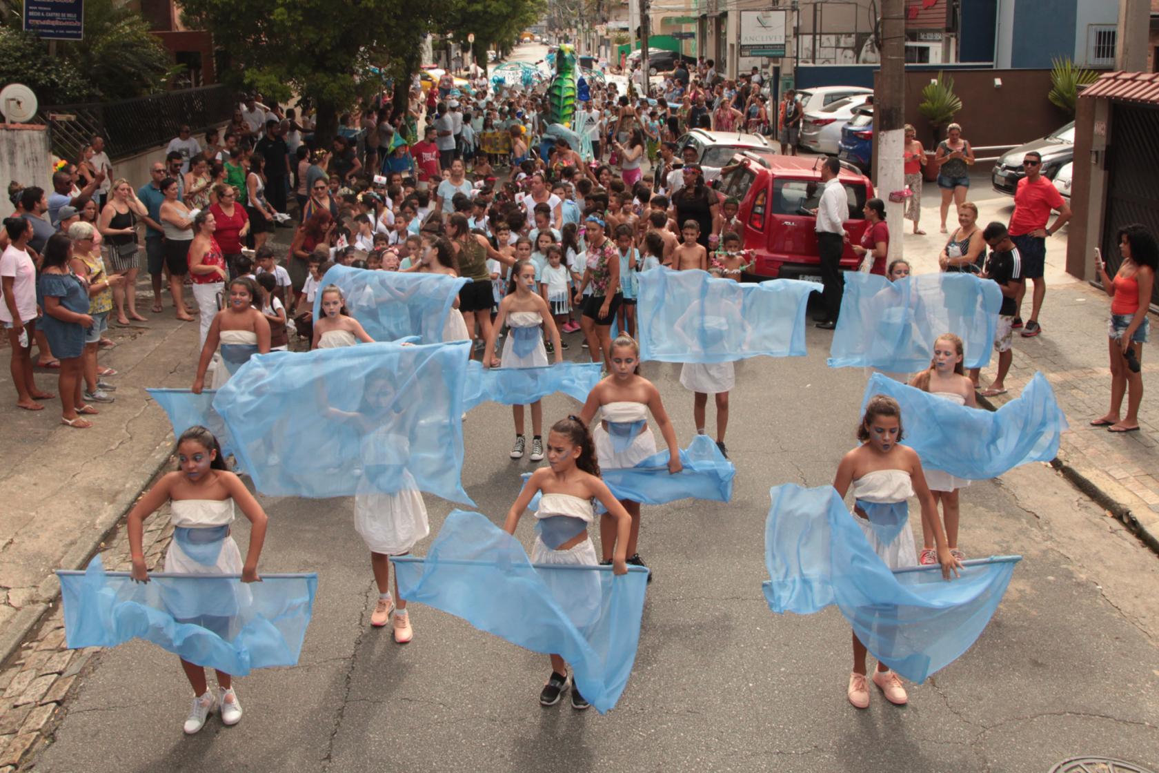 Crianças desfilam pela rua com fantasias. #paratodosverem