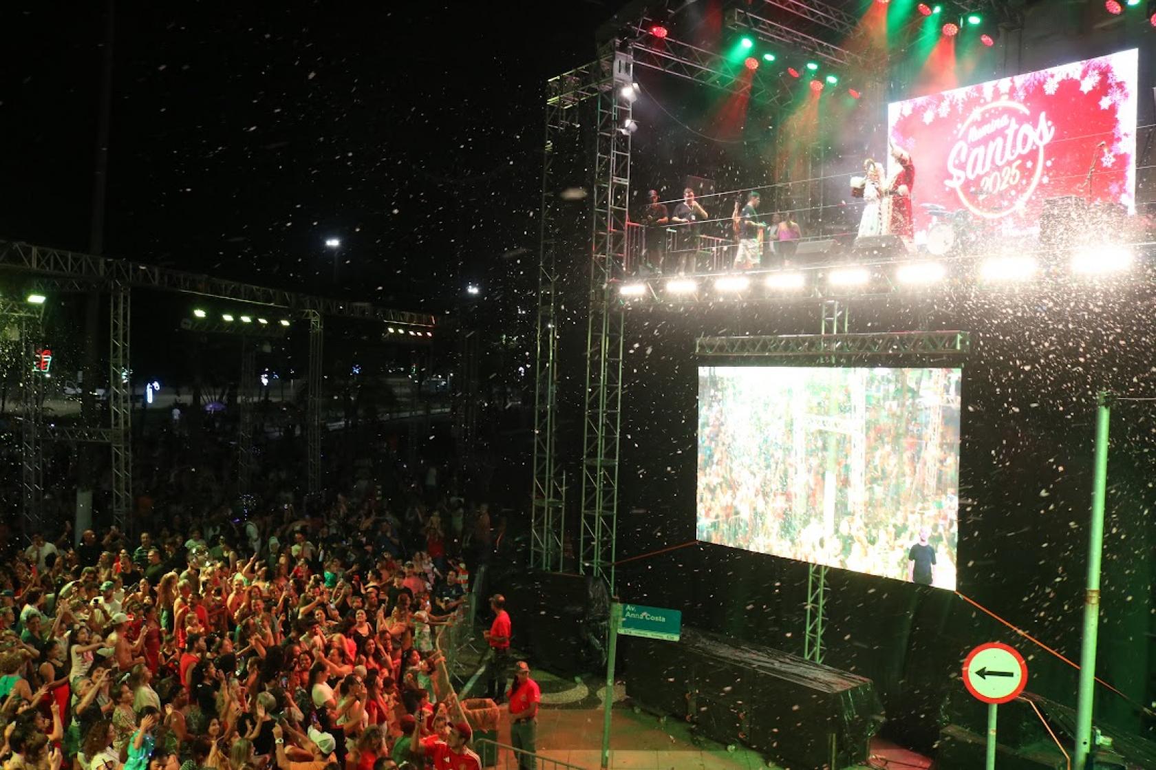 papai noel no palco com neve cenográfica caindo #paratodosverem