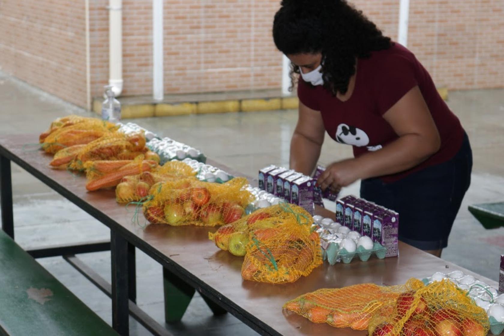 mulher separa alimentos para montar kit #paratodosverem
