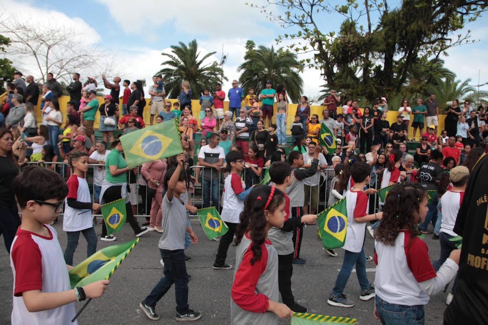 crianças desfilam pela avenida com bandeiras #paratodosverem