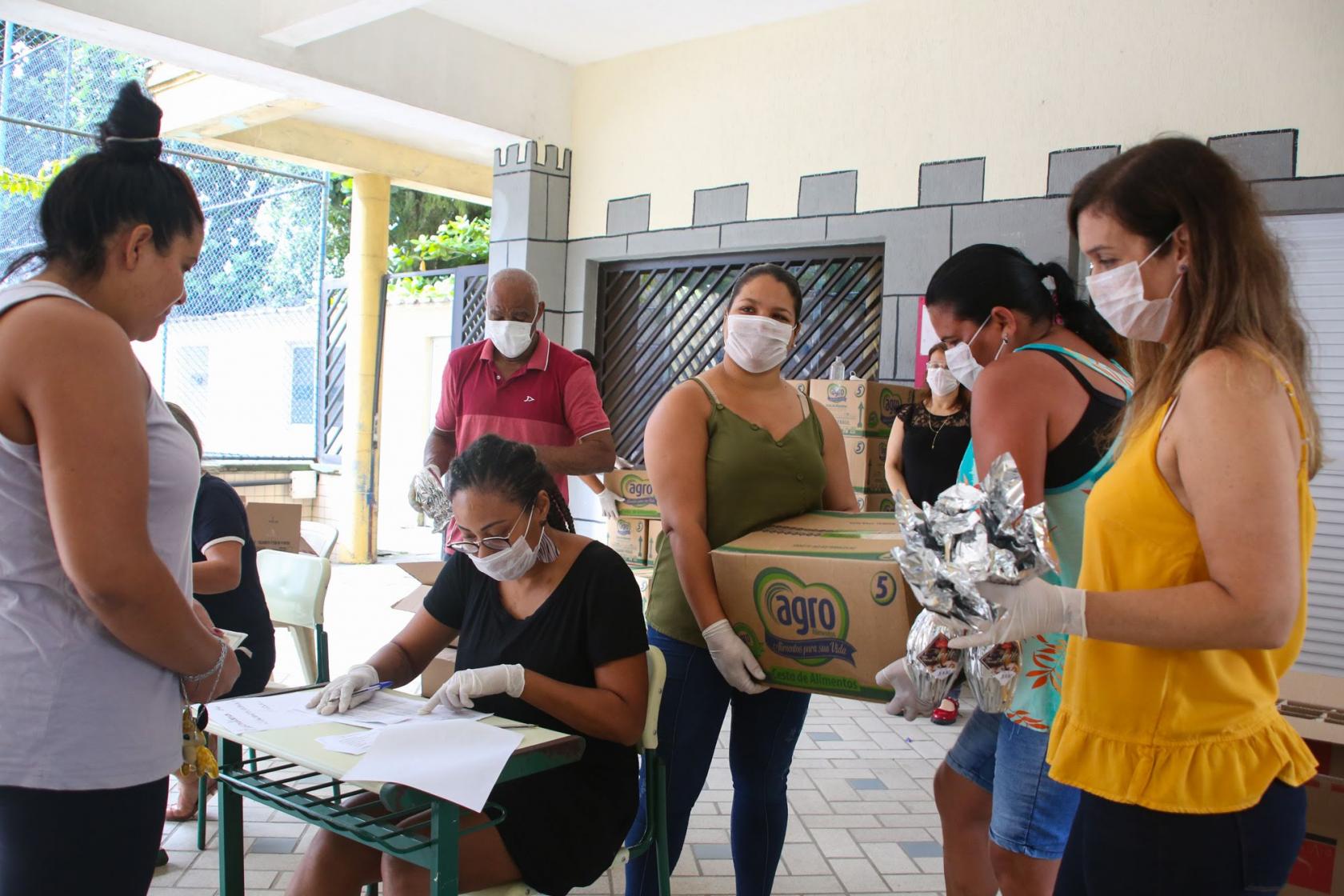 pessoas de máscara recebem as cestas #paratodosverem 