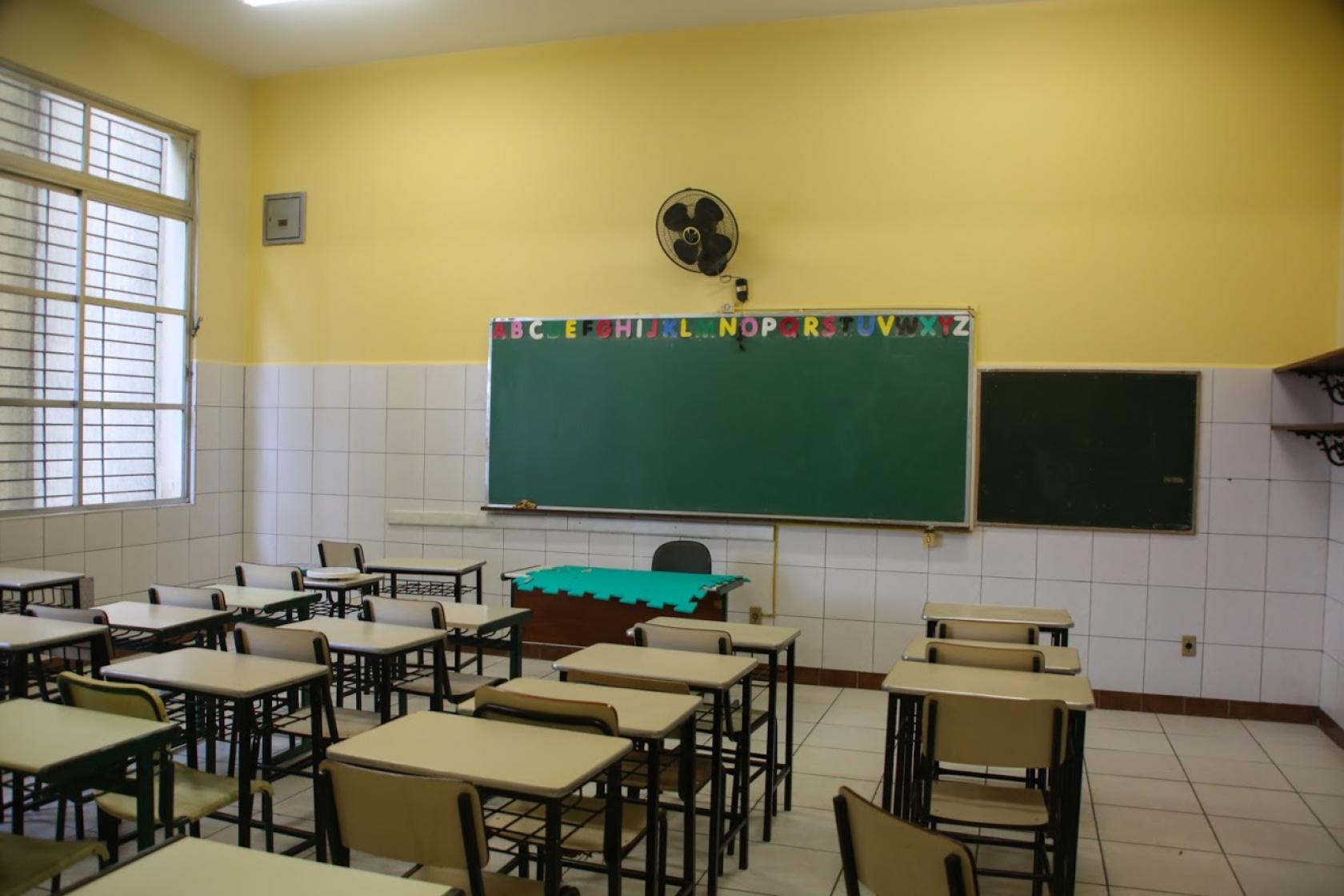 Sala de aula com nova pintura. As carteiras dos alunos estão dispostas organizadamente. Há lousa no fundo. #Paratodosverem