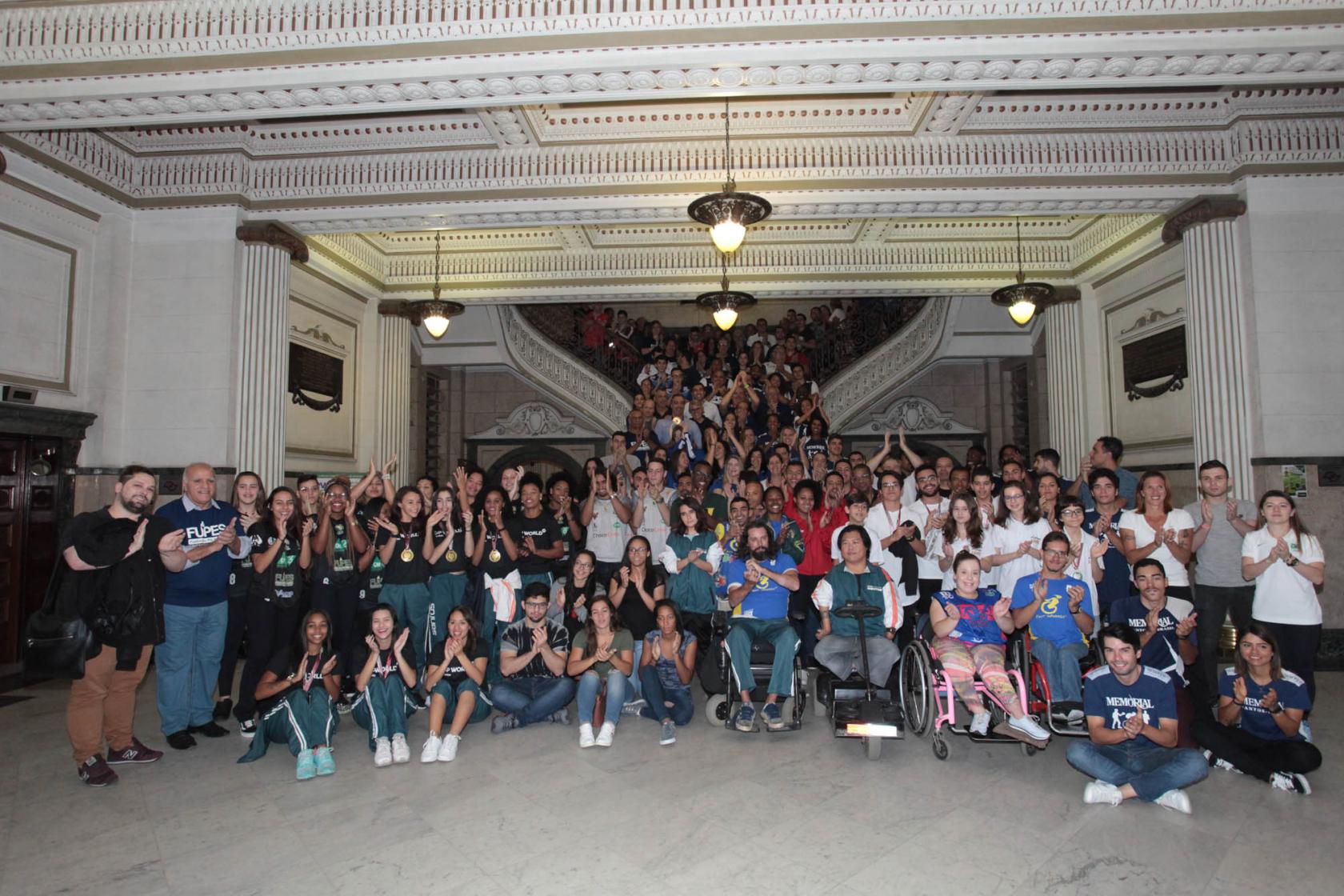 O grande grupo de atletas posa para foto no hall de entrada do paço municipal. #Pracegover