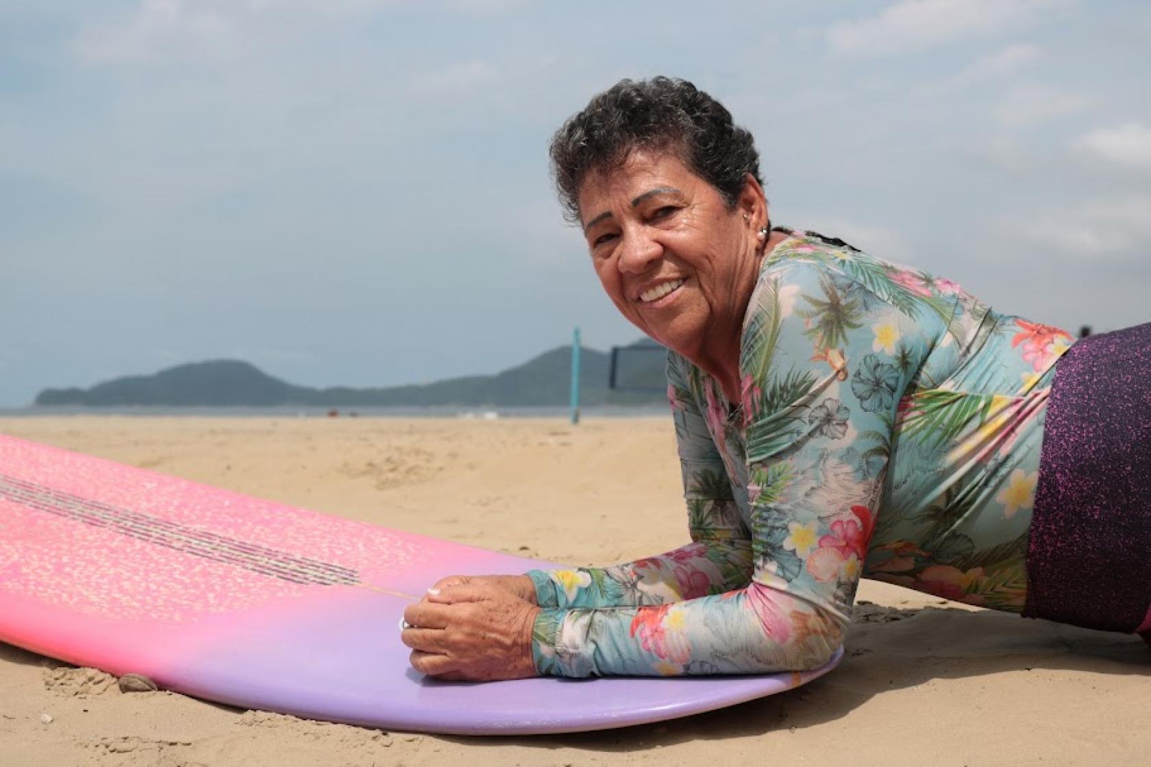 mulher deitada em prancha de surf #paratodosverem