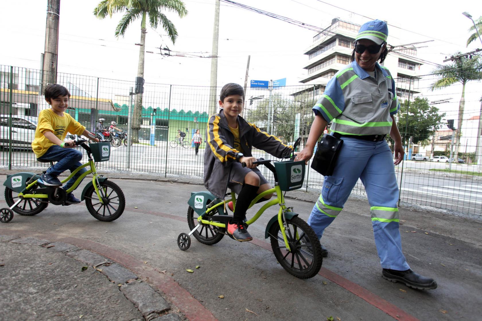 Agente ajuda menino a trafegar de bicicleta na pista #pracegover
