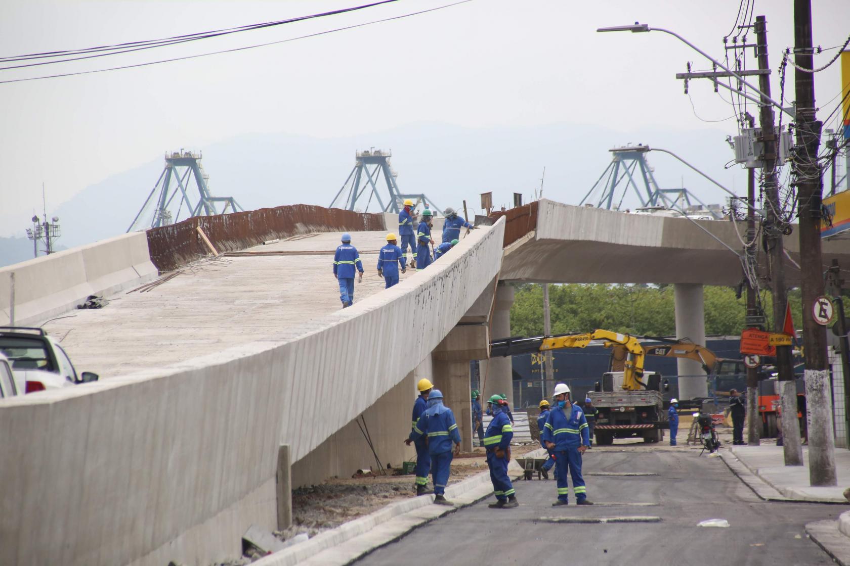 operários caminham sobre e ao lado de viaduto semi pronto #paratodosverem 