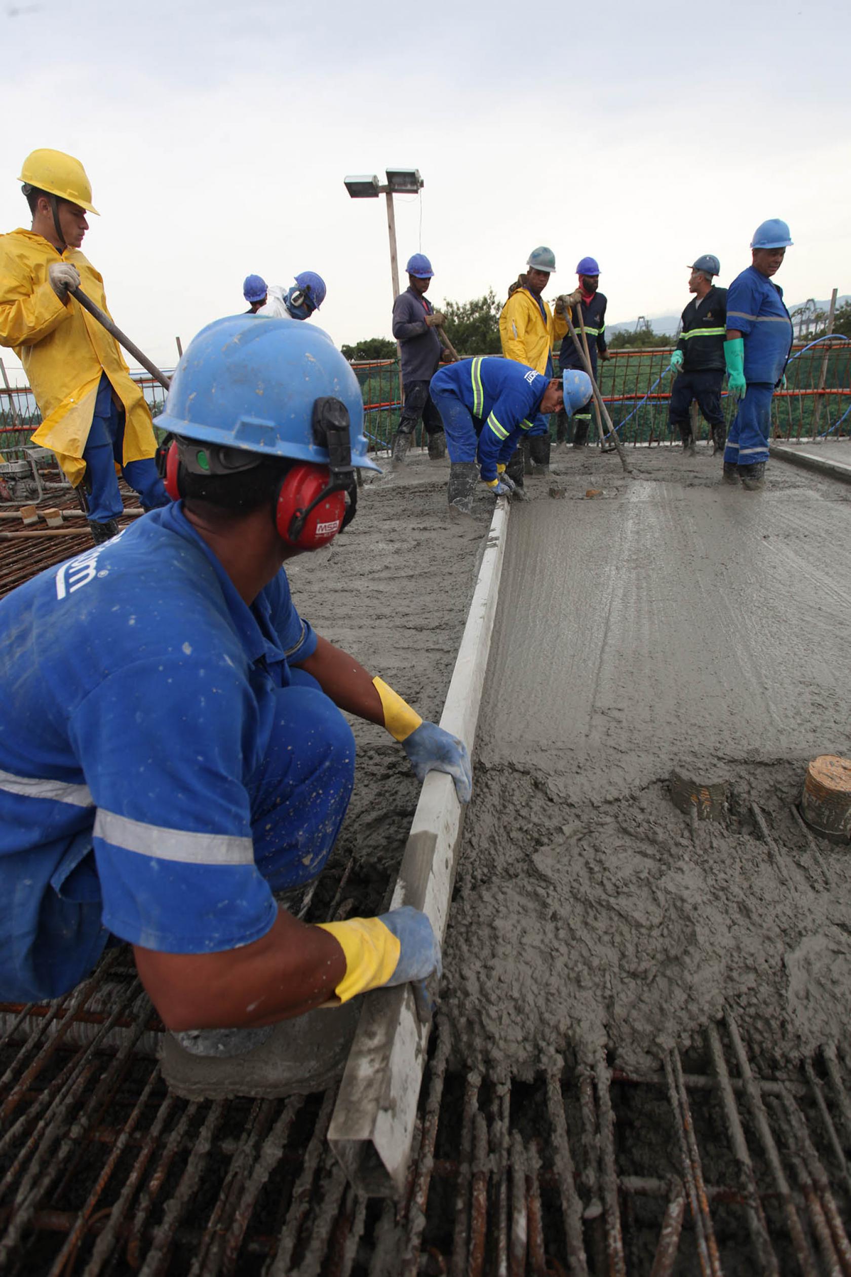 operários seguram cano durante a concretagem #pracegover