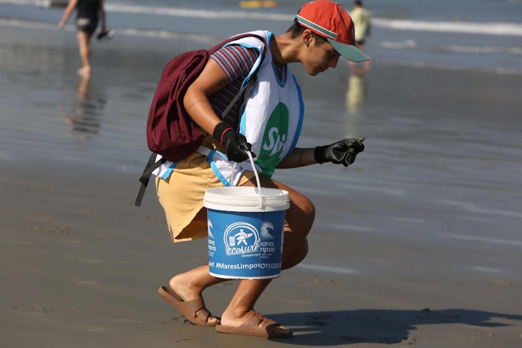 pessoa retira lixo da praia #paratodosverem 