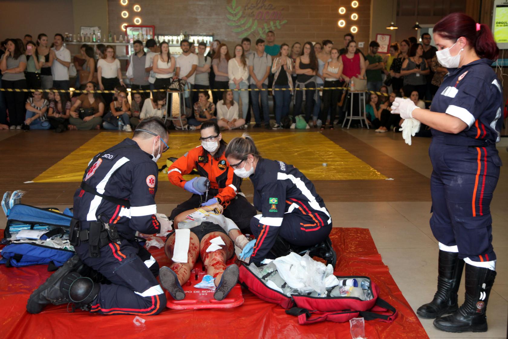 atendentes do samu simulam socorro, observados por alunos #pracegover