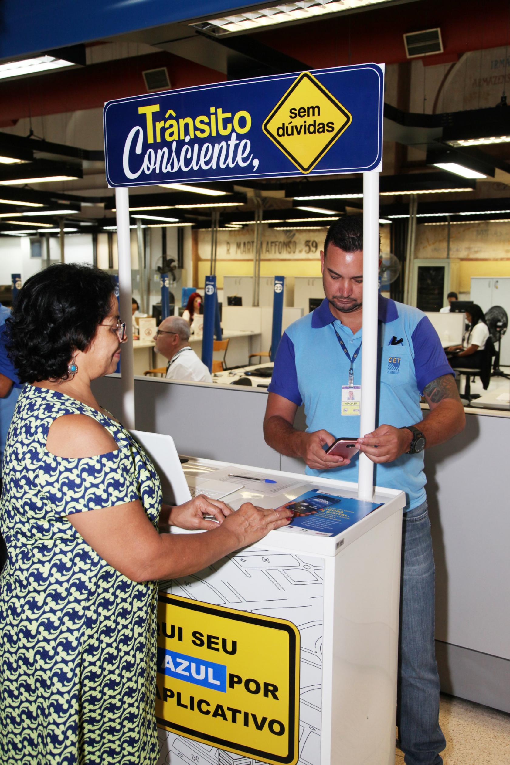 mulher está no ponto onde agente orienta sobre a zona zul #pracegover 