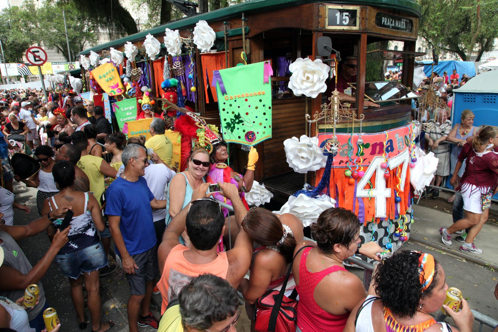 O bonde decorado está na praça rodeado de pessoas. #paratodosverem