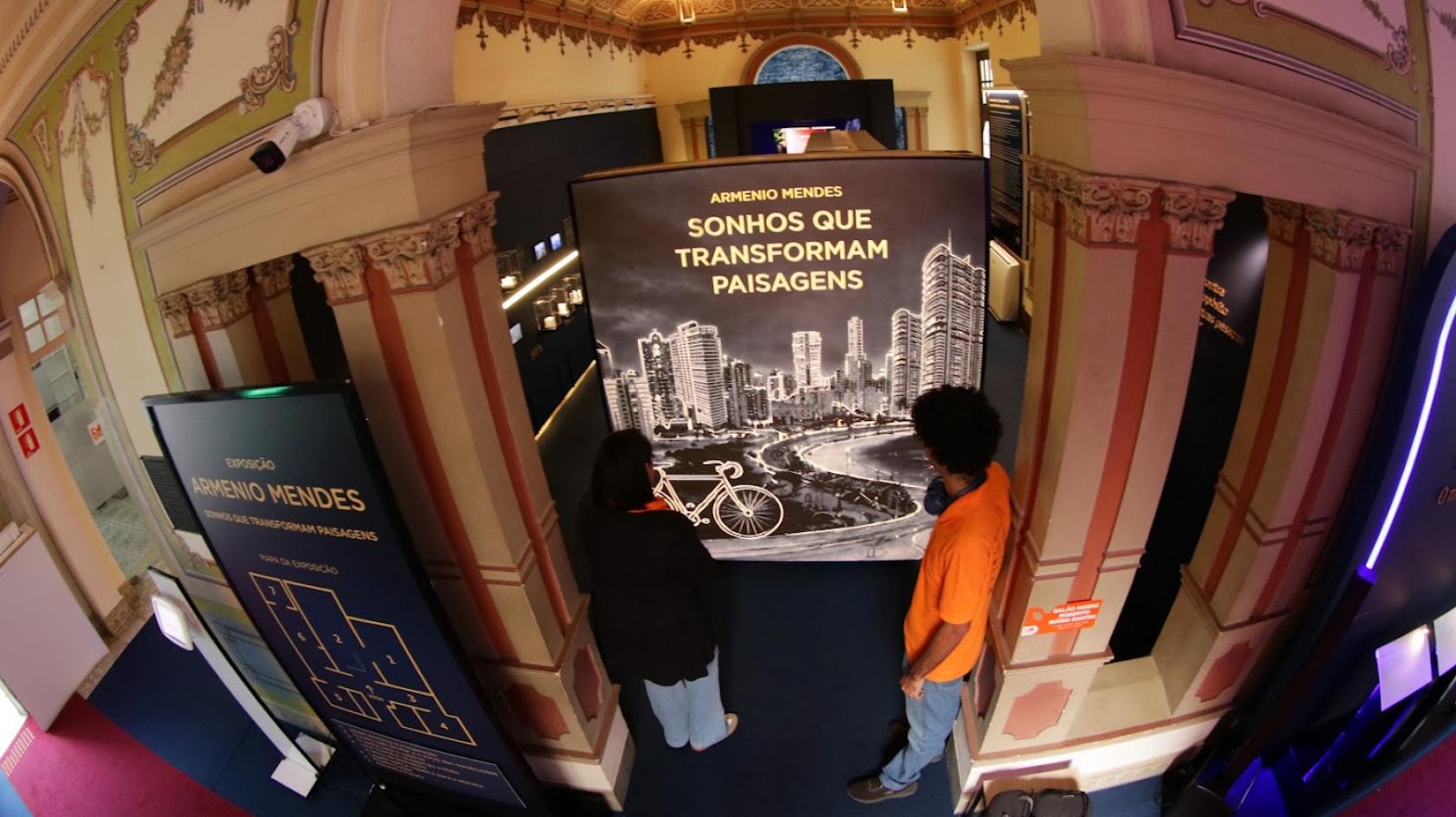 pessoas olhando a exposição #paratodosverem 