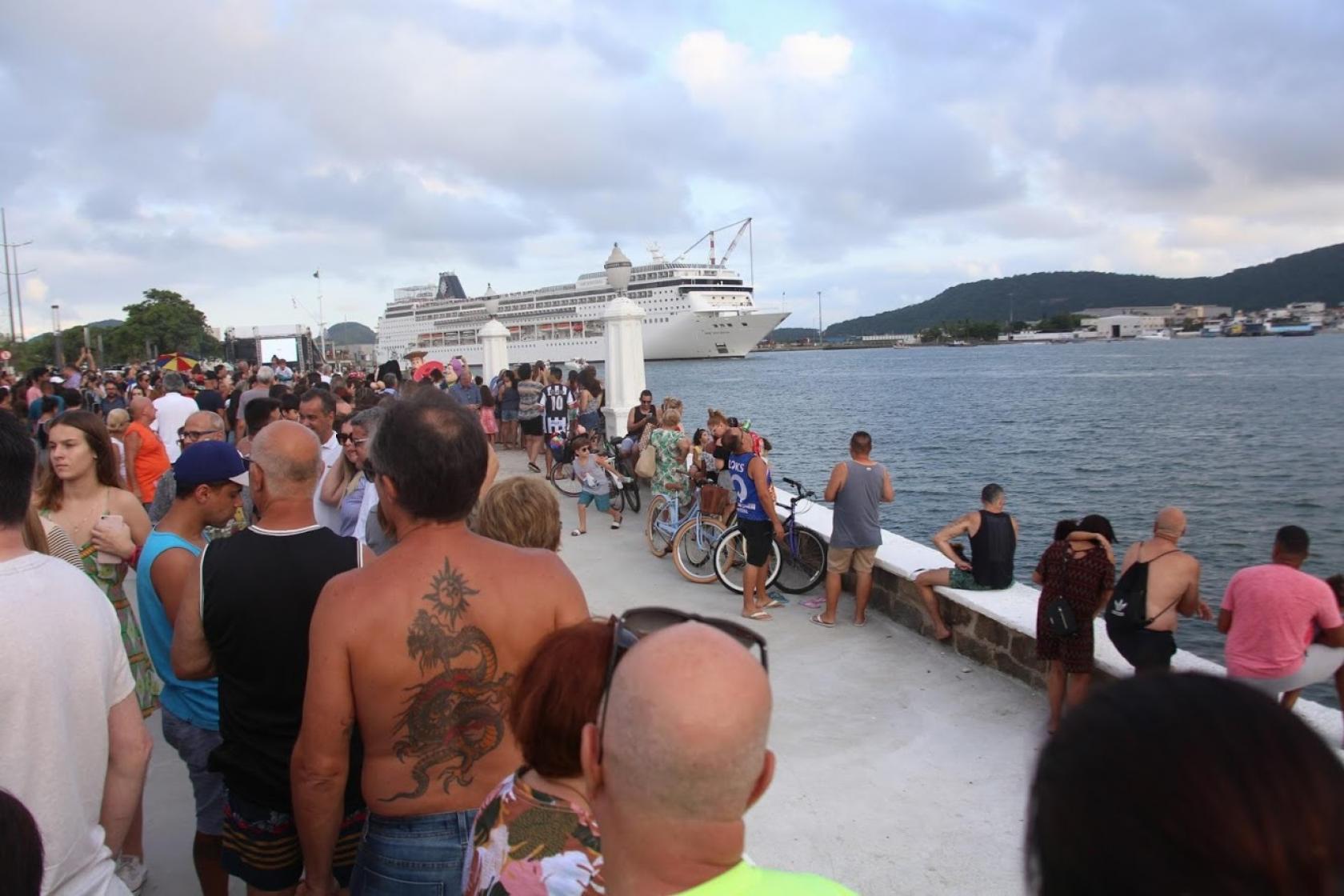 Calçadão de frente para o mar. navio de cruzeiro ao fundo e grande público e primeiro plano. #Pracegover