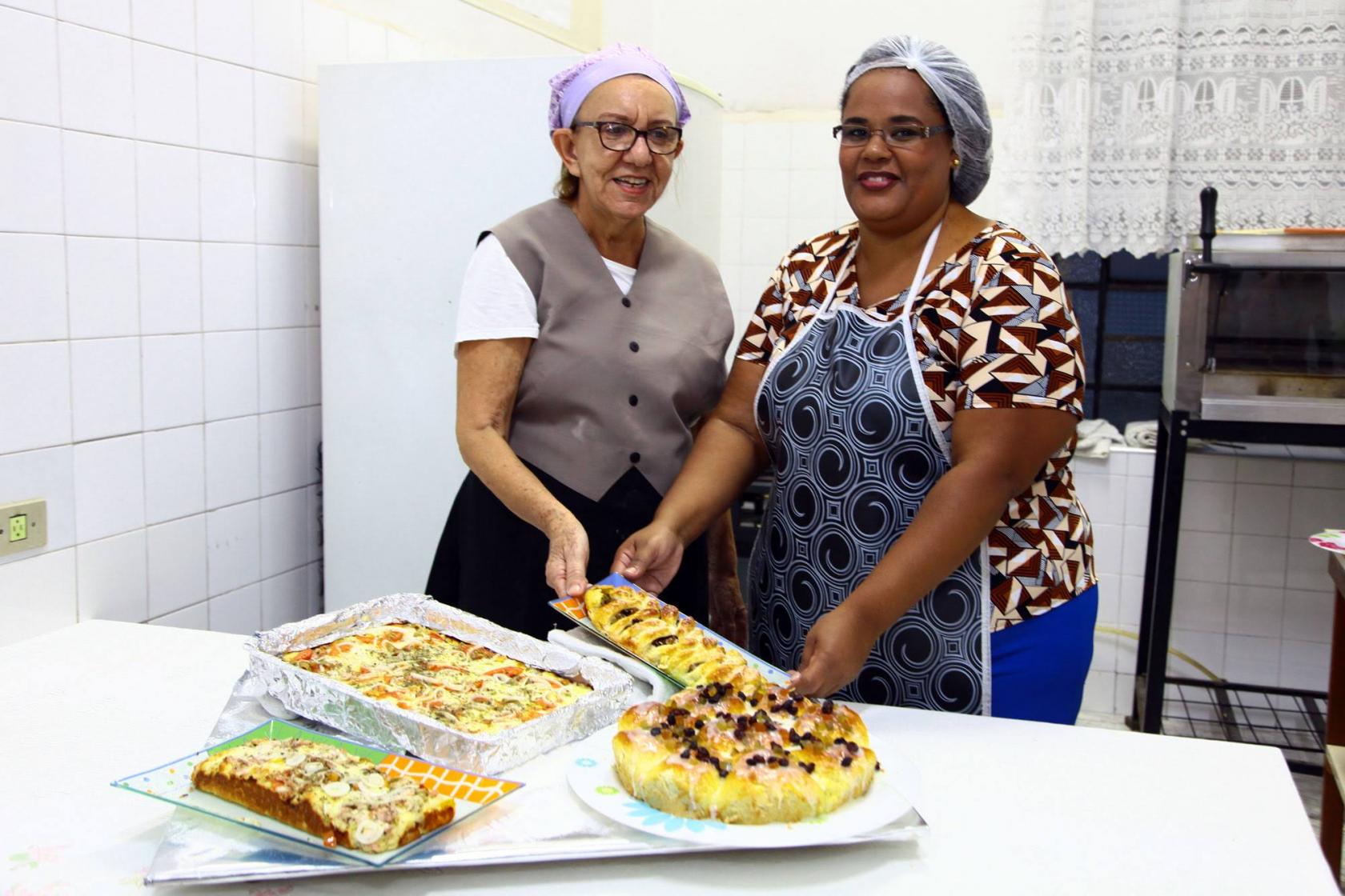 voluntárias posam ao lado de bolos #pracegover