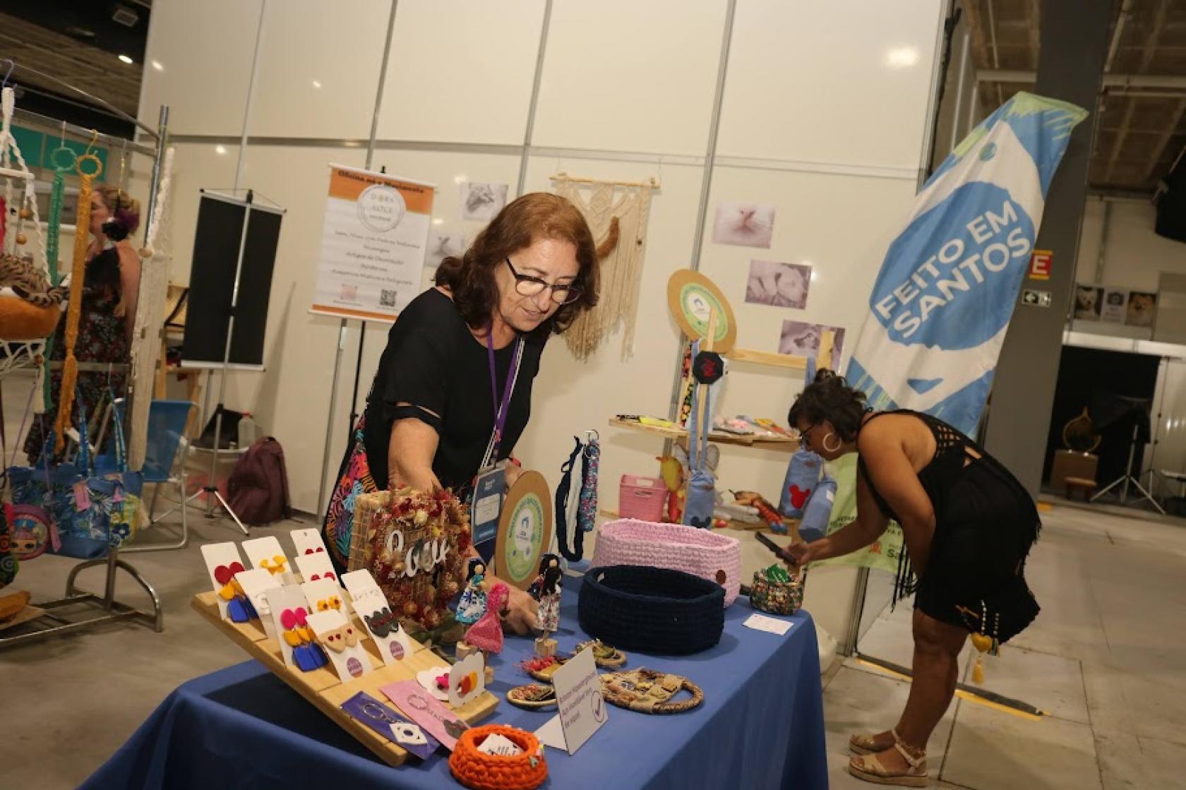 pessoas olham produtos em feira #paratodosverem