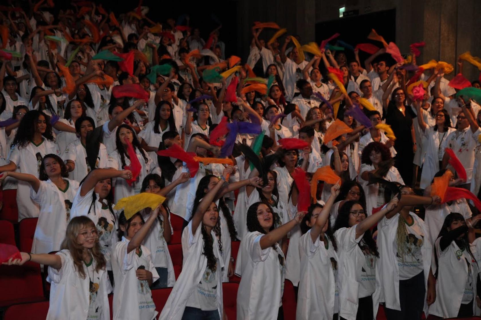 jovens com jalecos abanam lenços #paratodosverem