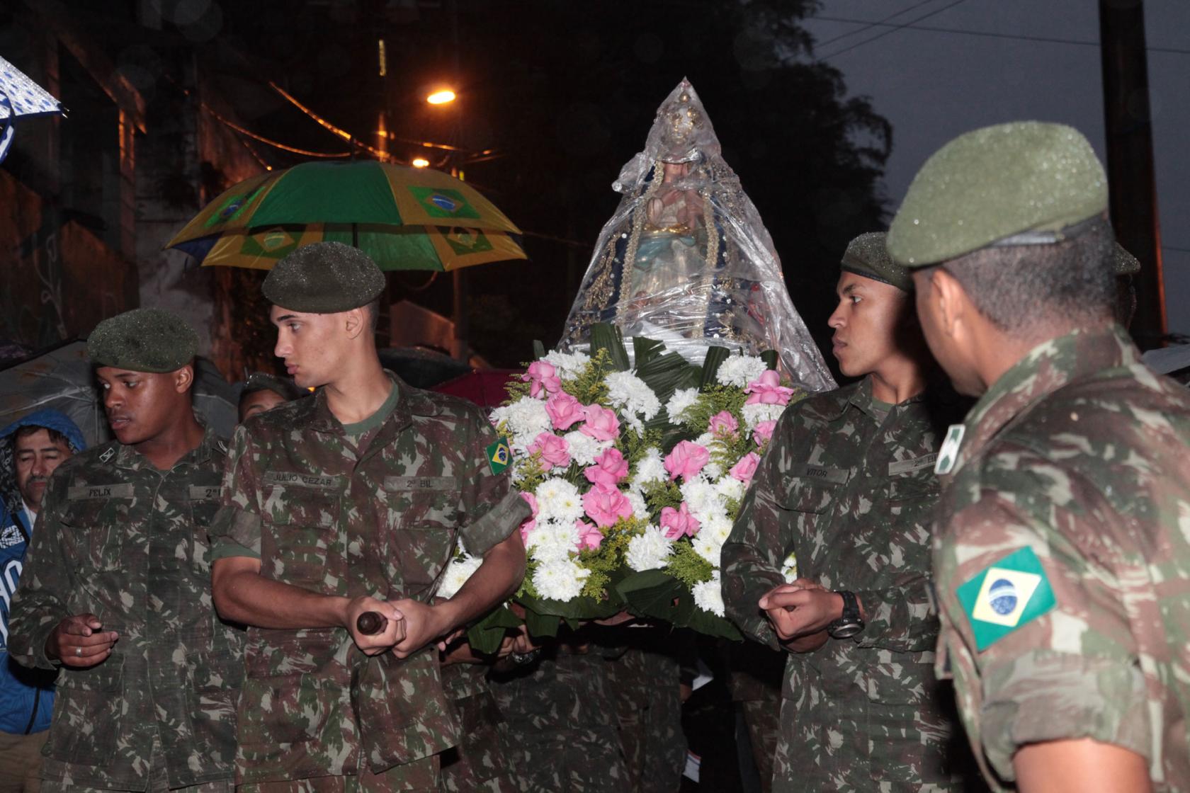Soldados do Exercito carregam imagem da Santa que está rodeada por flores. #Pracegover