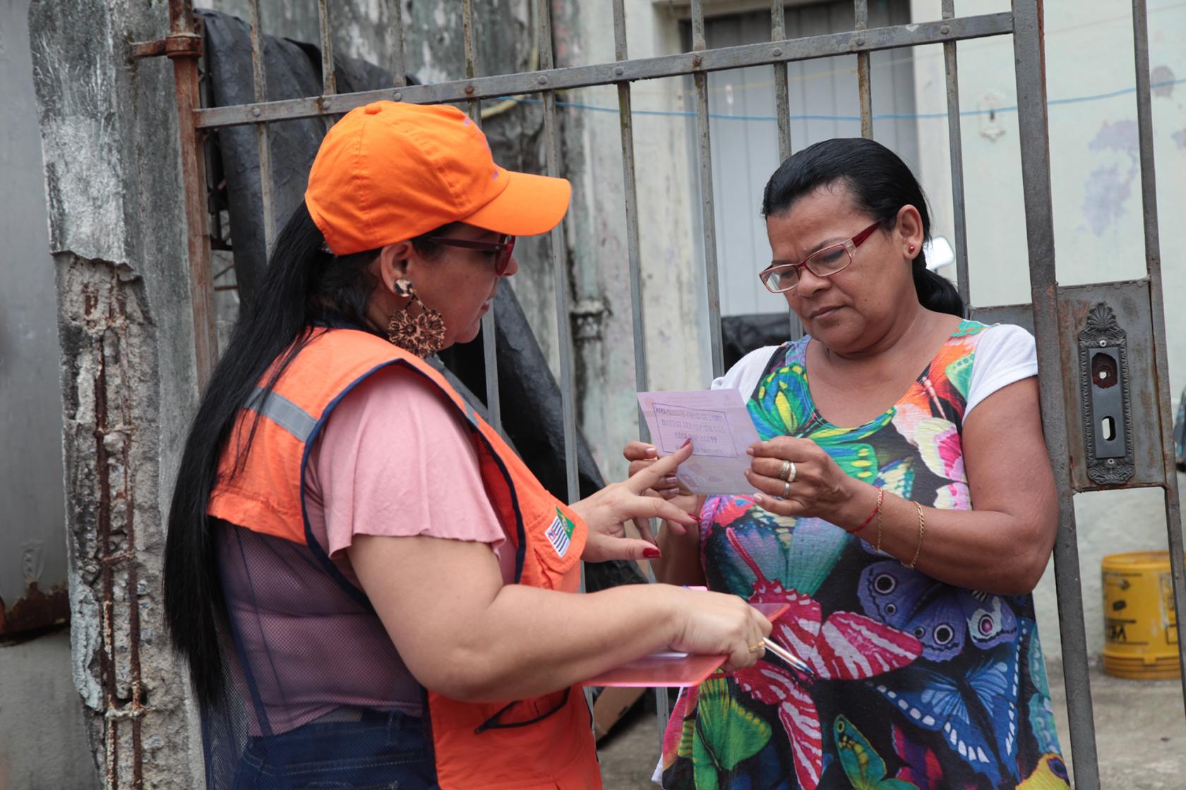 técnica da defesa civil entrega panfleto a mulher #pracegover