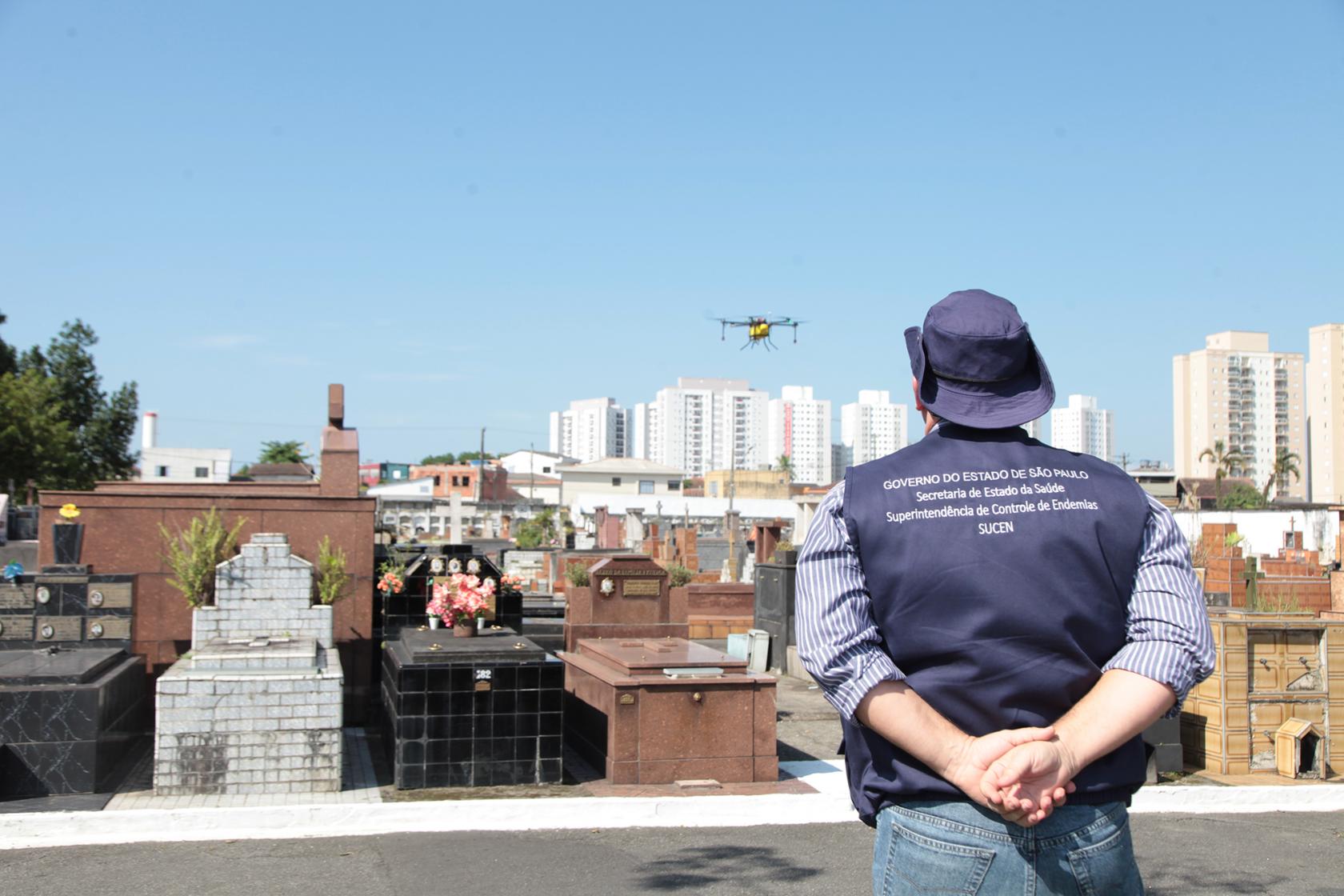 técnico observa o drone voando sobre túmulos #pracegover