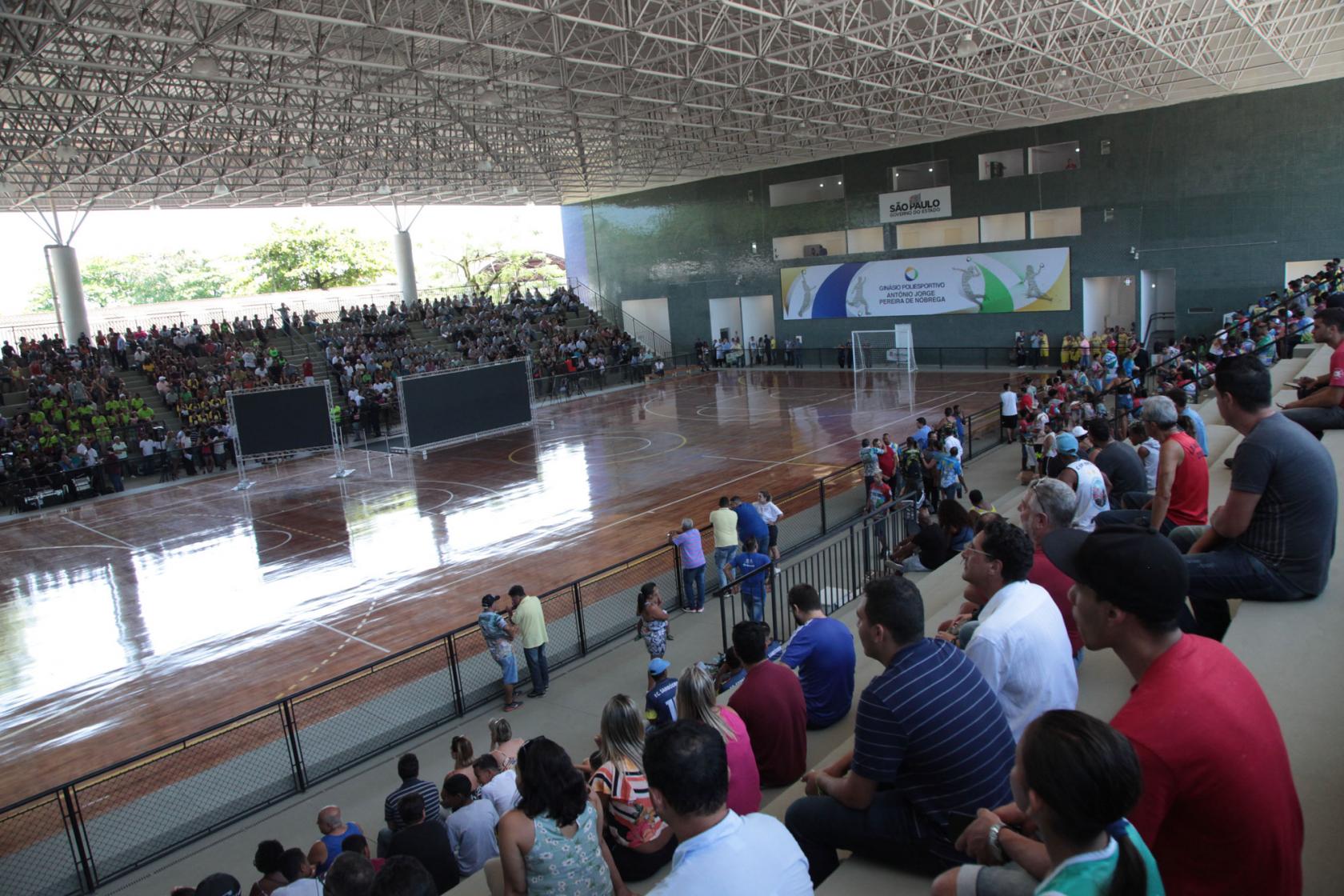 Vista geral do ginásio, com pessoas lotando a arquibancada. #Pracegover