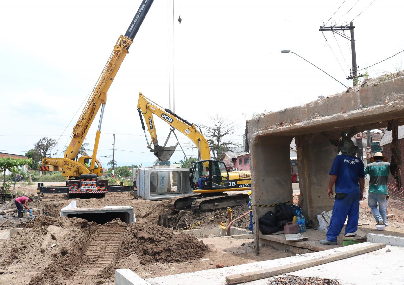 máquinas trabalham enquanto homem observa dentro de estrutura de concreto #paratodosverem 