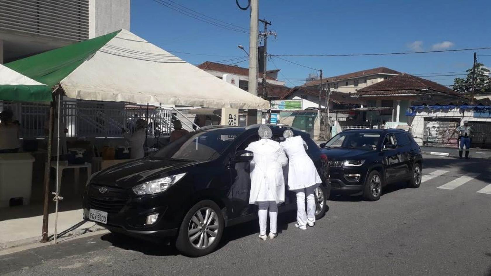 profissionais de saúde vacinam pessoas em carros #paratodosverem