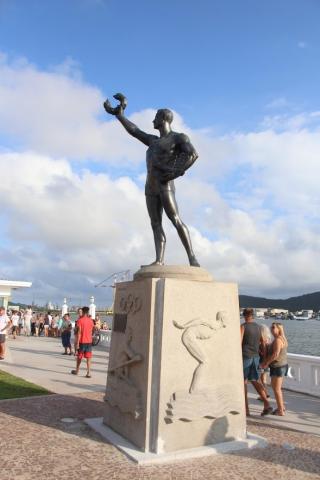 Monumento em homenagem ao atleta náutico. Ele está sobre um pedestal e segura um ramo de louros na mão direita. #Pracegover
