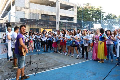 Homens com instrumentos de corda se apresentam a pessoas que o assistem em pé