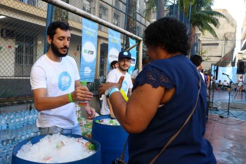 Atrás de balde de gelo, voluntário serve refrigerante a mulher