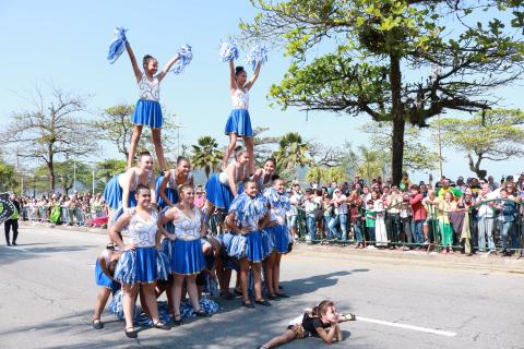 Meninas uniformizadas fazem acrobacias na avenida. Elas formam uma espécie de pirâmide humana. #Pracegover