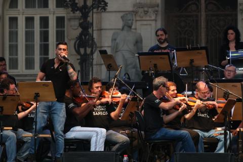 Cristopher Clark, à esquerda da image, cantando junto à orquestra. #Pracegover