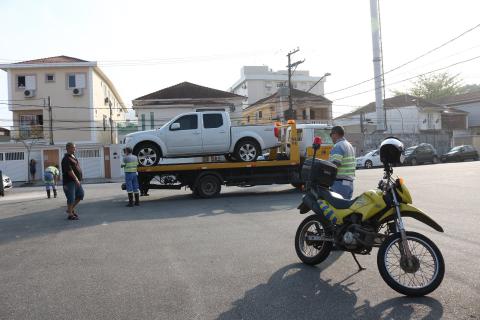 Moto viatura está em primeiro plano. Ao fundo, um carro recém-guinchado está sobre o veículo que o removerá. #Pracegover