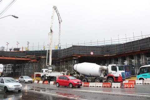 Estacionado ao lado do viaduto caminhão possui manqueira que chega ao topo da estrutura para aplicação de concreto