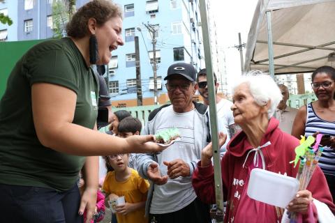 Constância recebe pedaço de bolo das mão de uma mulher