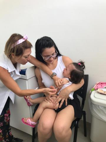 menina é vacinada enquanto mãe a segura no colo #pracegover