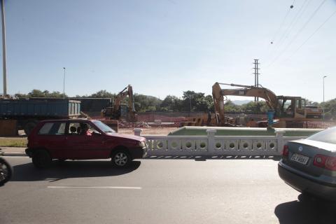 carros passam em avenida na frente de máquina atuando na obra #paratodosverem 