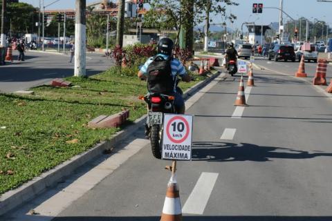 Motociclistas percorrem faixa exclusiva sinalizada no solo e por cones que indicam velocidade máxima. #Paratodosverem