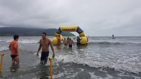 Atletas saem da água; ao fundo, o novo pórtico inflável de chegada. #pracegover