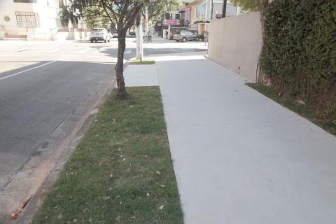 Trecho de calçada com espaço para pedestre e faixa verde próxima à gua. #Paratodosverem