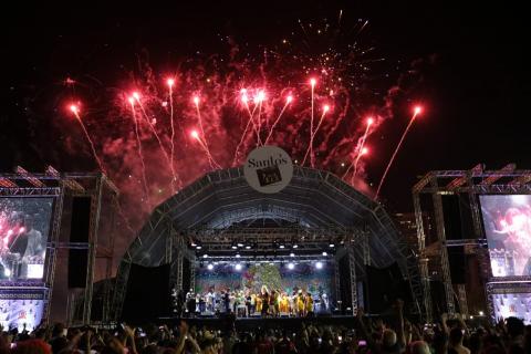 Palco dos show iluminado no topo pela queima de fogos de artifício. #Pracegover