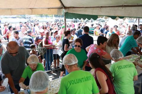 Voluntárias do Fundo Social cortam o bolo de aniversário para distribuir à população. #pracegover