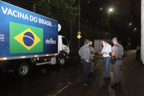 Caminhão parado com pessoas e policiais militares ao lado. #paratodosverem