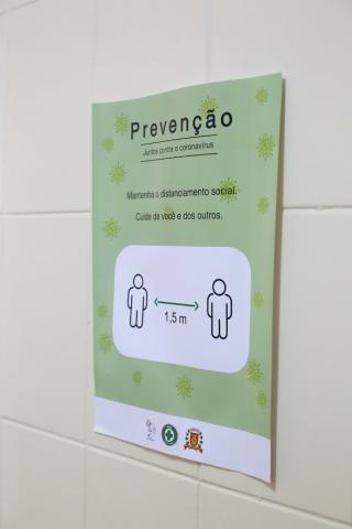 cartaz fixado em parede com orientação sobre necessidade de distanciamento entre pessoas. #Paratodosverem