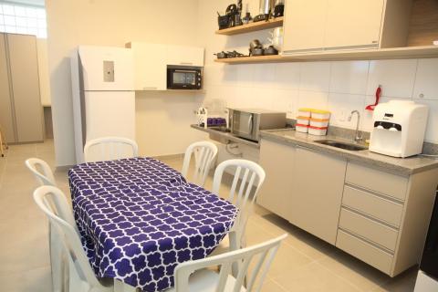 Cozinha com mesa e cadeiras, armários, geladeira e forno micro-ondas. #Paratodosverem