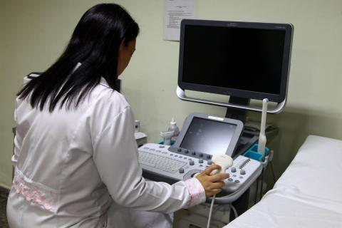 Enfermeira sentada em frente ao aparelho de ultrassom. #pracegover