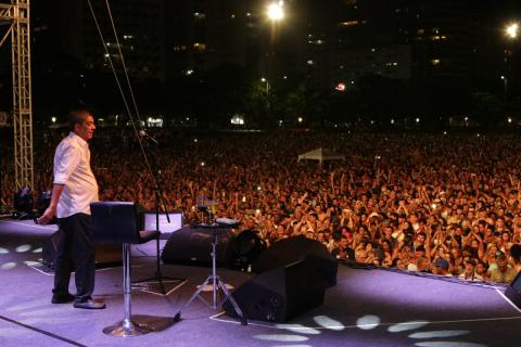 O cantor Zega Pagodinho no palco com o grande público ao fundo. #Pracegover
