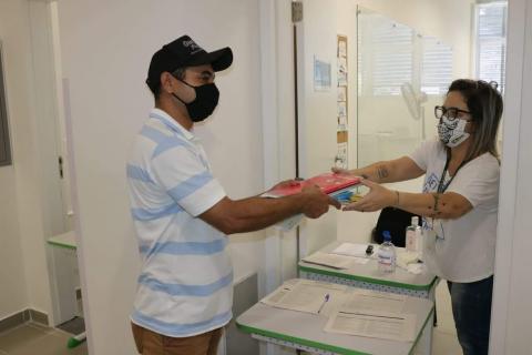 Homem recebe material das mãos de uma mulher. #Paratodosverem